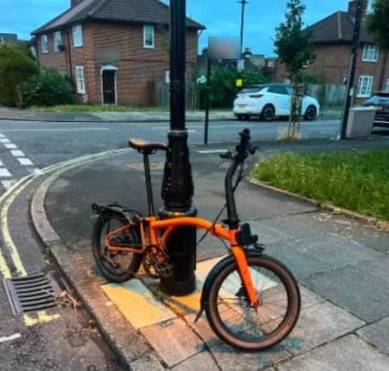 Nikitas's orange Brompton, found by a lamp post on a residential street